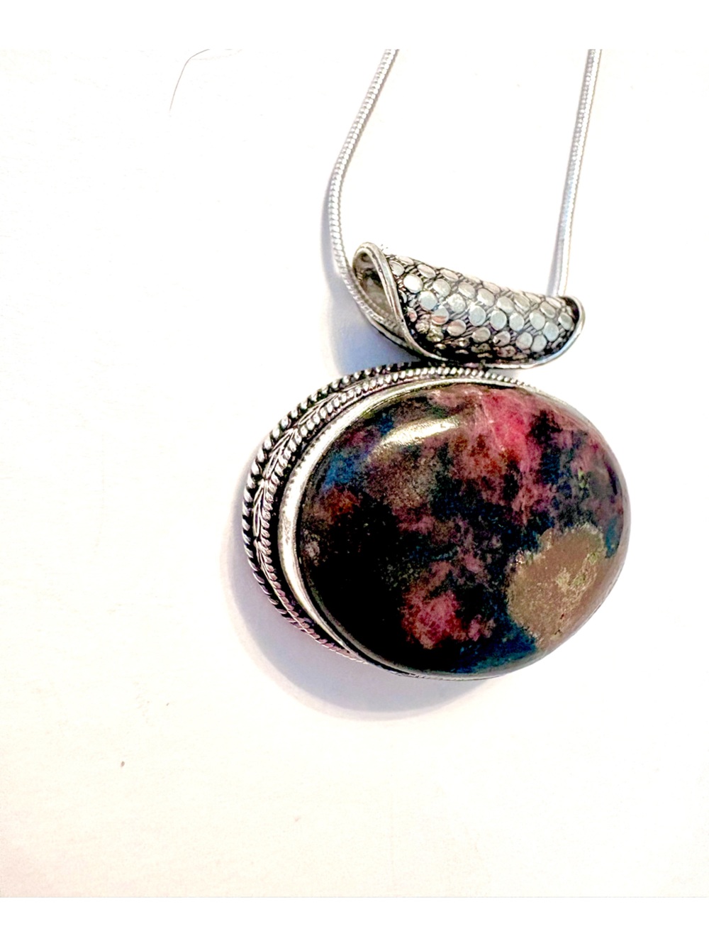 925 marked, Rhodonite pendant with a pretty design around, on a silver chain.